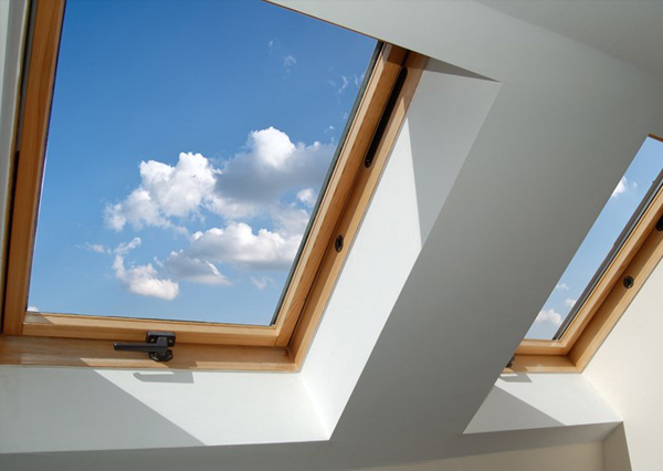 Two skylight windows with wooden frames give a clear view to a blue sky with white clouds